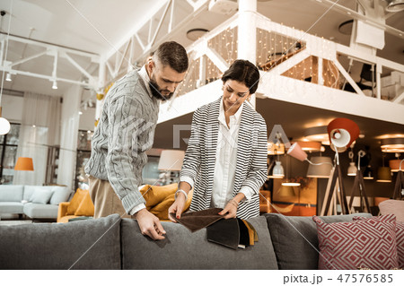 Attentive bearded dark-haired man looking on piece of fabric Attentive bearded dark-haired man looking on piece of fabric 47576585