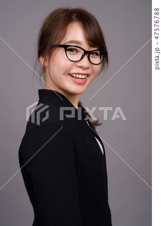 Young beautiful Asian businesswoman against gray background 47576788