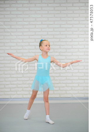 Little ballerina in blue dress and pointe shoes is dancing in ballet school. Cute girl in dance 47578053