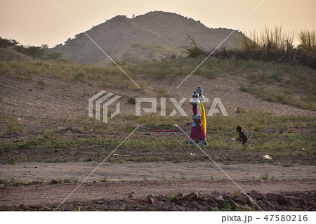インドのラジャスタン州 夕暮れのプシュカル 水瓶を頭に乗せて運ぶインド人女性と手伝う少年 インドのラジャスタン州 夕暮れのプシュカル 水瓶を頭に乗せて運ぶインド人女性と手伝う少年 47580216