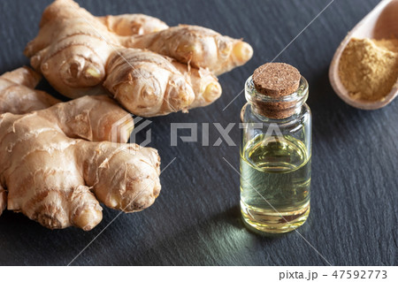 A bottle of ginger essential oil with fresh ginger 47592773