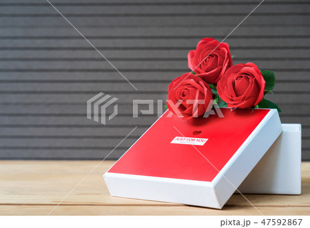 Red roses and heart-shaped box on wood background 47592867