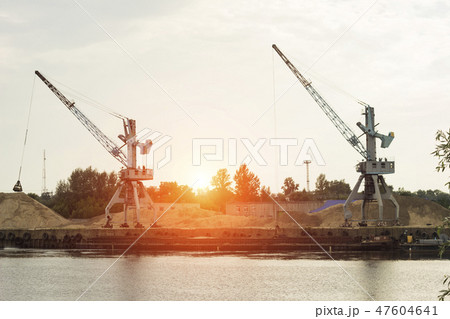 Two port cranes at the riverbank produce river sand, sunset, barge Two port cranes at the riverbank produce river sand, sunset, barge 47604641