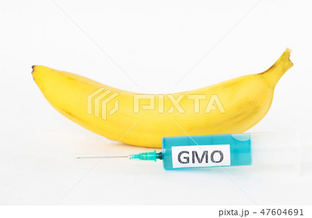 Banana on a white background next to which is a syringe with gmo and nitrates, close-up, nitrates 47604691