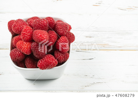 Plate with raspberry on rustic White background. 47608279