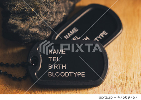 Soldier tag or dog tag laid on brown wooden table. 47609767