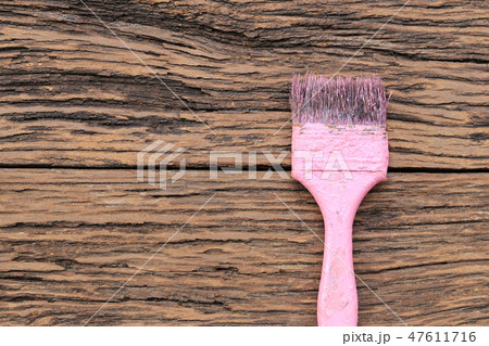 Old pink paint brush on brown wooden floor. 47611716