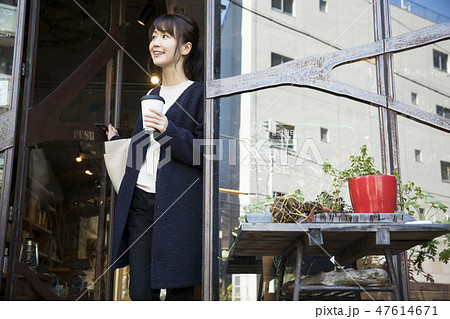 コーヒーをテイクアウトして店を出る女性 47614671