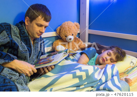 Dad reads book to daughter at night 47620115