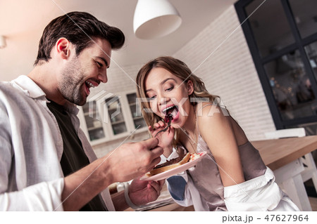 Dark-haired bearded man in a white shirt and his pretty wife looking happy Dark-haired bearded man in a white shirt and his pretty wife looking happy 47627964