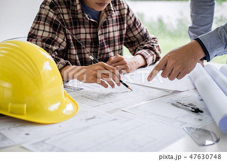 Construction engineering or architect discuss a blueprint while 47630748