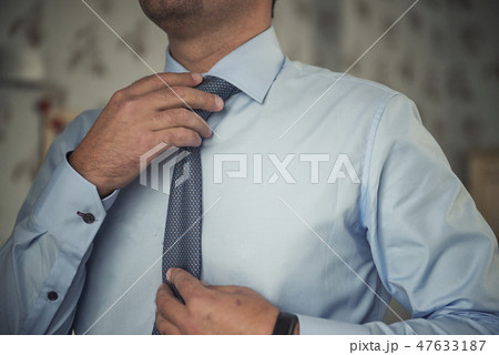 Man adjusting his necktie 47633187
