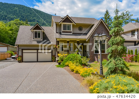 Big family house with concrete driveway, two garage doors, decorated front yard Big family house with concrete driveway, two garage doors, decorated front yard 47634420