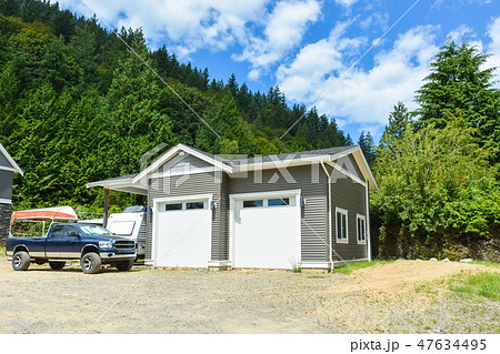 Brand detached double garage with car and boat parked on gravel driveway Brand detached double garage with car and boat parked on gravel driveway 47634495