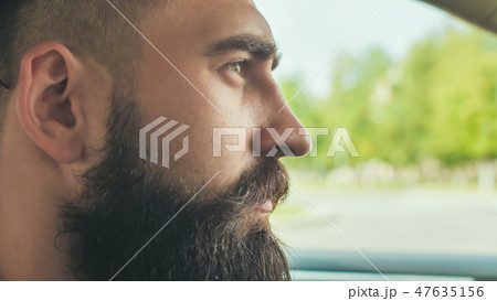A brutal bearded man drives a car. 47635156
