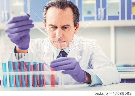 Ageing chemist placing test tubes in order 47639005