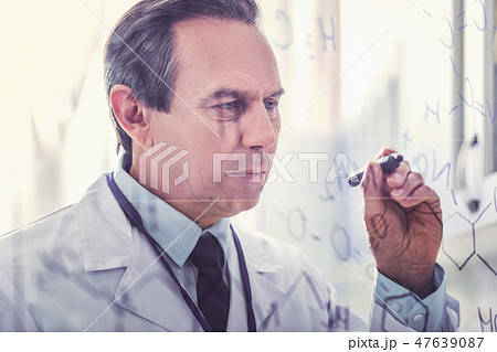 Ageing microbiologist holding marker pen writing formula Ageing microbiologist holding marker pen writing formula 47639087