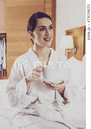 Pleasant lady sitting on comfortable bed Pleasant lady sitting on comfortable bed 47639620