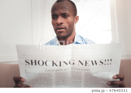 Pleasant surprised man reading a newspaper Pleasant surprised man reading a newspaper 47640331