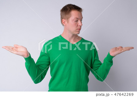 Portrait of young handsome man comparing something 47642269