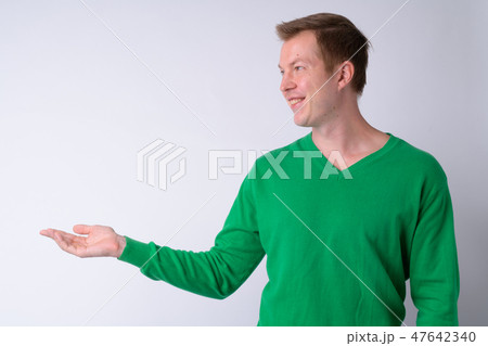 Profile view of happy young handsome man showing something 47642340