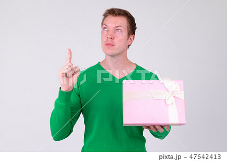 Young handsome man thinking while pointing up with gift box ready for Valentine's day Young handsome man thinking while pointing up with gift box ready for Valentine's day 47642413
