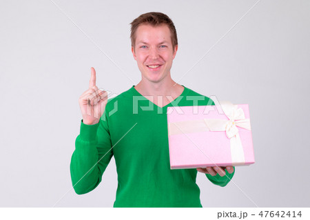 Happy young man pointing up with gift box ready for Valentine's day 47642414