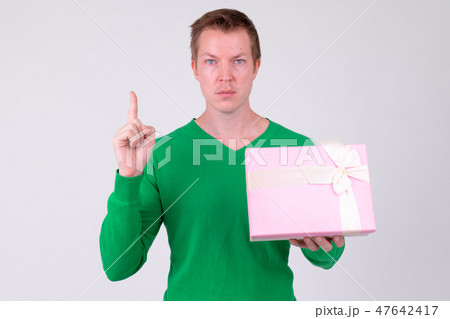 Young handsome man pointing up with gift box ready for Valentine's day 47642417
