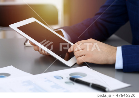 Businessman using tablet at meeting, closeup of hands. Business operations concept Businessman using tablet at meeting, closeup of hands. Business operations concept 47645520