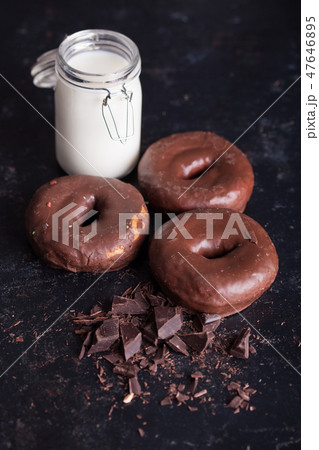 Chocolate donuts near bottle of milk and chocolate crumbs. 47646895