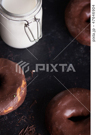 Chocolate donuts near bottle of milk and chocolate crumbs. 47646904
