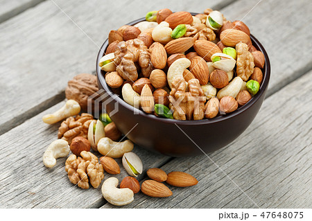 Wooden bowl with mixed nuts on a wooden gray Wooden bowl with mixed nuts on a wooden gray 47648075