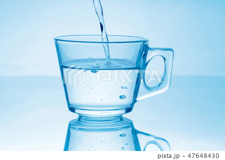 Flowing pure water into glass on blue Flowing pure water into glass on blue 47648430