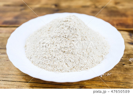 Close-up heap with wheat flour coarse in white plate on wooden background Left on the photo Top view Close-up heap with wheat flour coarse in white plate on wooden background Left on the photo Top view 47650589