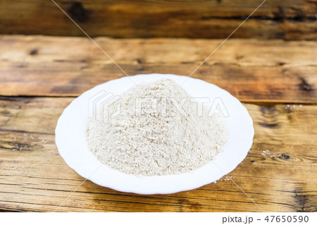 Close-up heap with wheat flour coarse in white plate on wooden background. 47650590