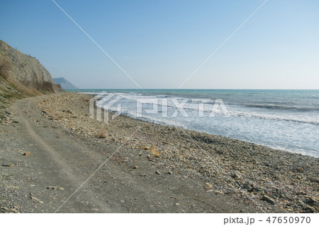 Pebble beach with mountains and cliffs. A windy day at sea. 47650970