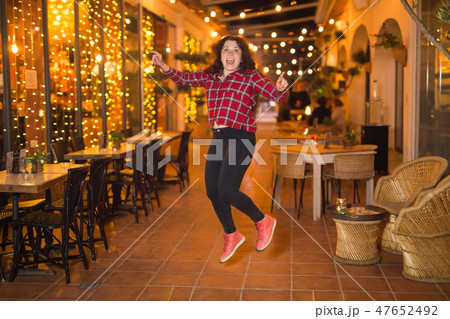 Nightlife, people and fun concept - Beautiful young woman poses near bright restaurant on the street 47652492