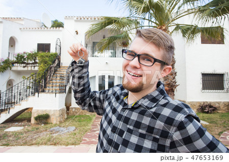 Ownership, real estate, property and tenant concept - Portrait of a cheerful young man holding key Ownership, real estate, property and tenant concept - Portrait of a cheerful young man holding key 47653169