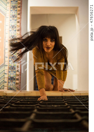 Beautiful Moroccan Girl in Short Golden Dress crawling by lattice indoor of Picturesque Dar Si Said 47656271