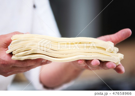 Pastry chef showing dough sheets ready to be rolled to produce croissant. 47658966