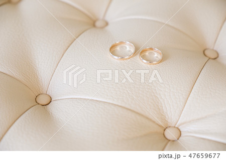 Wedding rings on a light leather sofa. Side view. 47659677