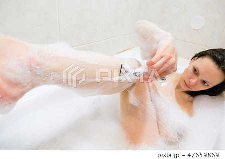 Beautiful young woman enjoying pleasant bath with foam Beautiful young woman enjoying pleasant bath with foam 47659869