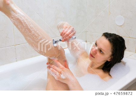 Beautiful young woman enjoying pleasant bath with foam 47659872