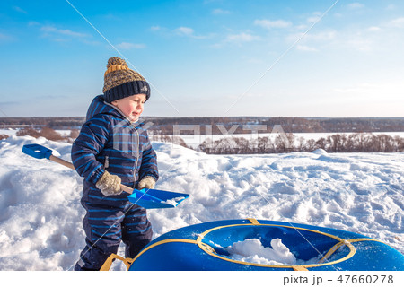 A little boy child plays in the snow in winter. Free space for text. In blue overalls and hat. On A little boy child plays in the snow in winter. Free space for text. In blue overalls and hat. On 47660278