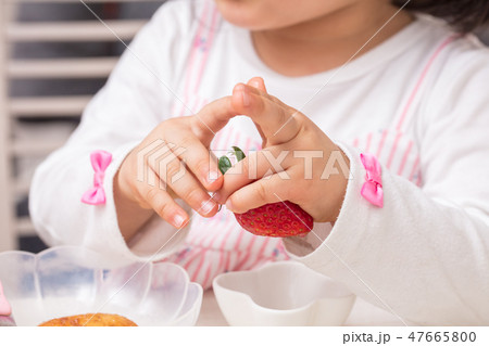 幼児の女の子いちごを持っていじいじしているの写真素材