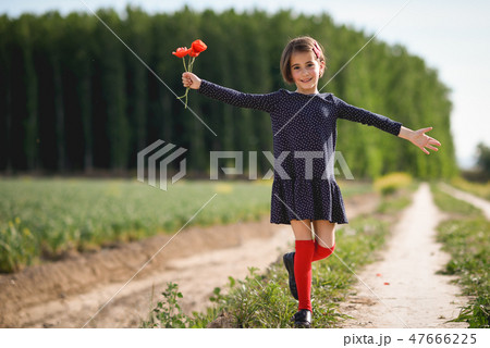 Little girl walking in nature field wearing beautiful dress 47666225