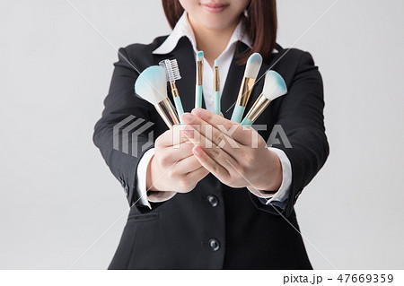 就活のスーツの女性がメイク道具セットを両手で持つの写真素材
