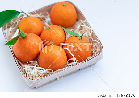 Tangerines with green leaves in a basket Tangerines with green leaves in a basket 47673176