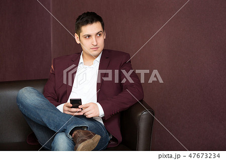 Young man in a red jacket with a phone in his hand. 47673234