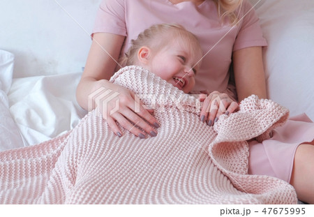 Young attractive blond mom plays hide and seek with her little charming daughter in pink dresses. 47675995